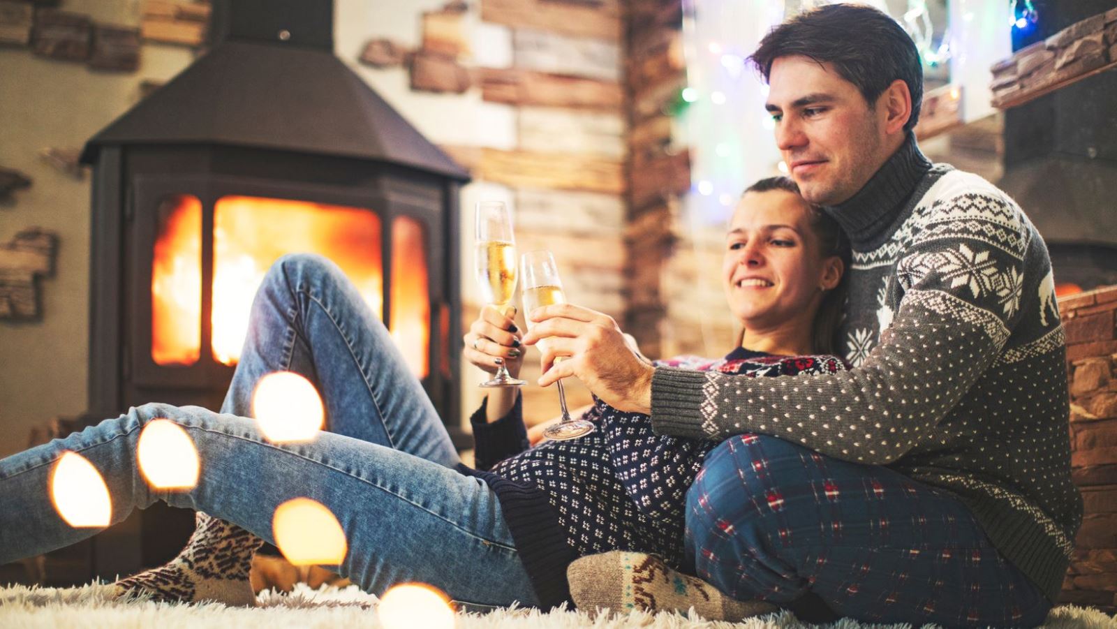 A couple sitting next to a warming fire in the fireplace